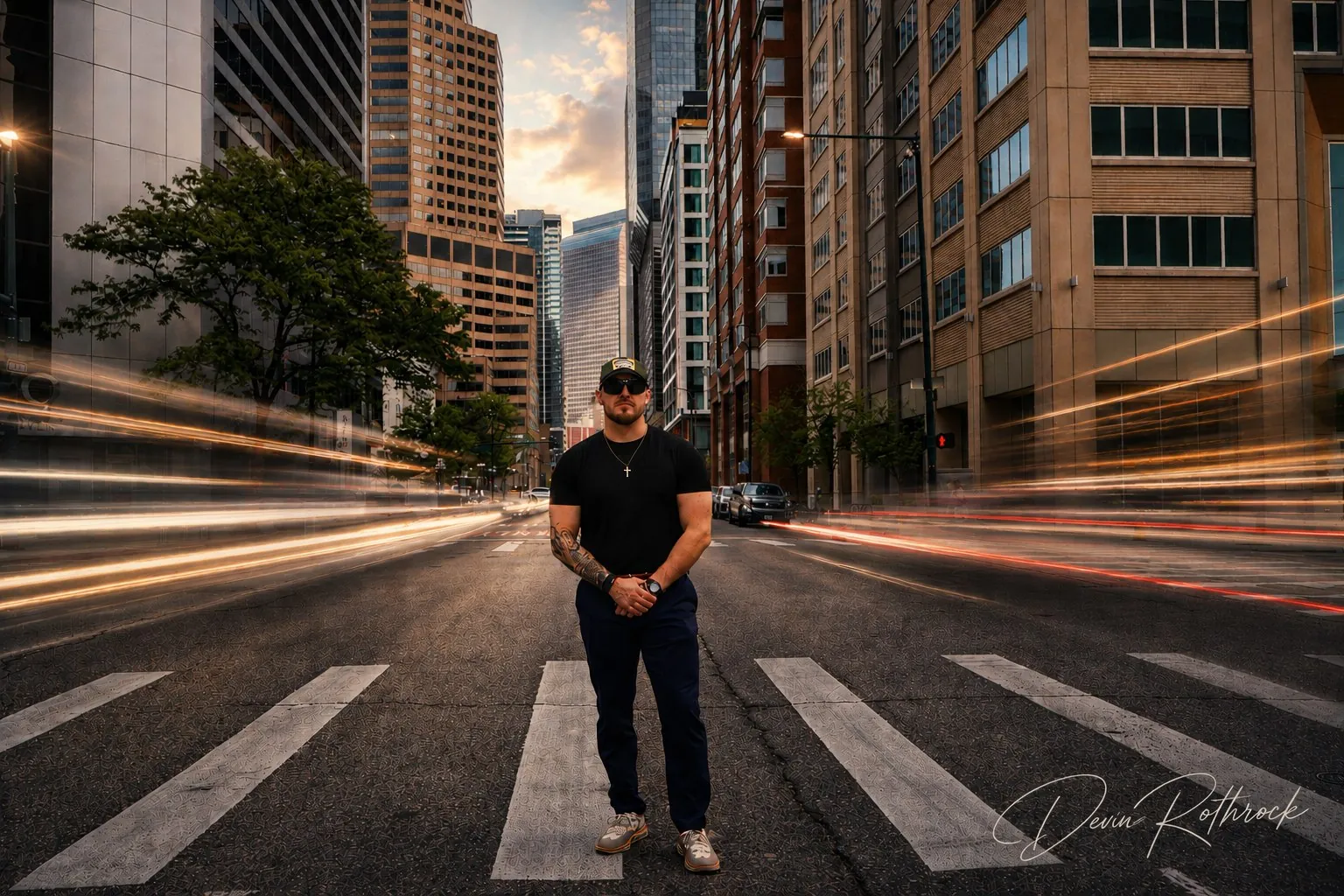 Devin Rothrock standing in a downtown Denver street at dusk with light trails